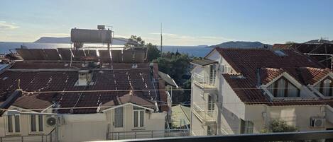 A residential area with multiple buildings, some with visible balconies and a clear view of the sea in the background.