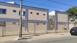 Un edificio moderno con entrada protegida por una reja, un plato de antena visible y un coche estacionado.
