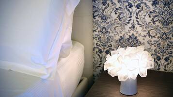 Un comodino con un vaso bianco e una lampada decorativa accesa.