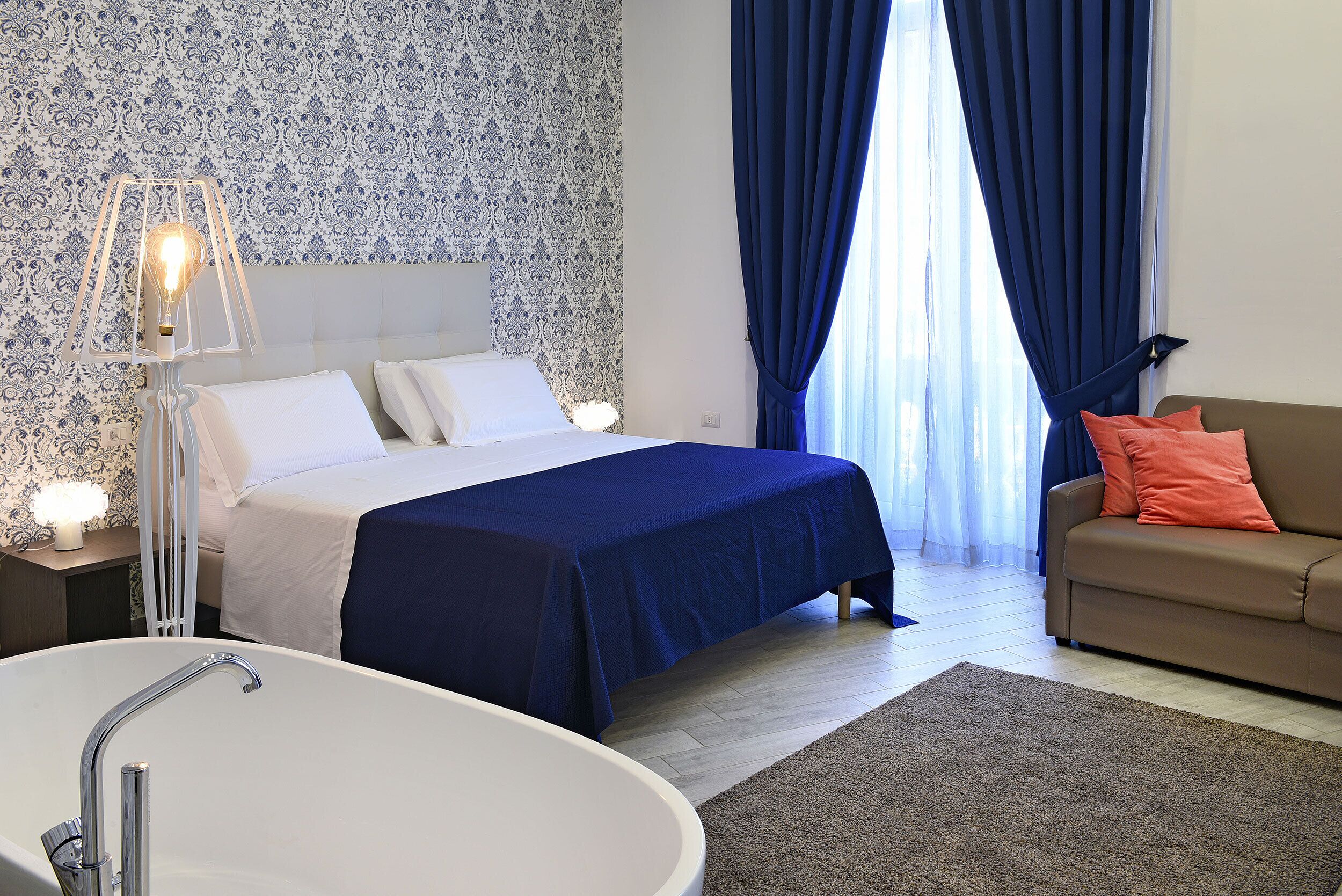 Un dormitorio con cama, sofá, bañera y pared con diseño.