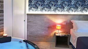 Una habitación moderna con bañera, una mesita de noche con lámpara y una cama.