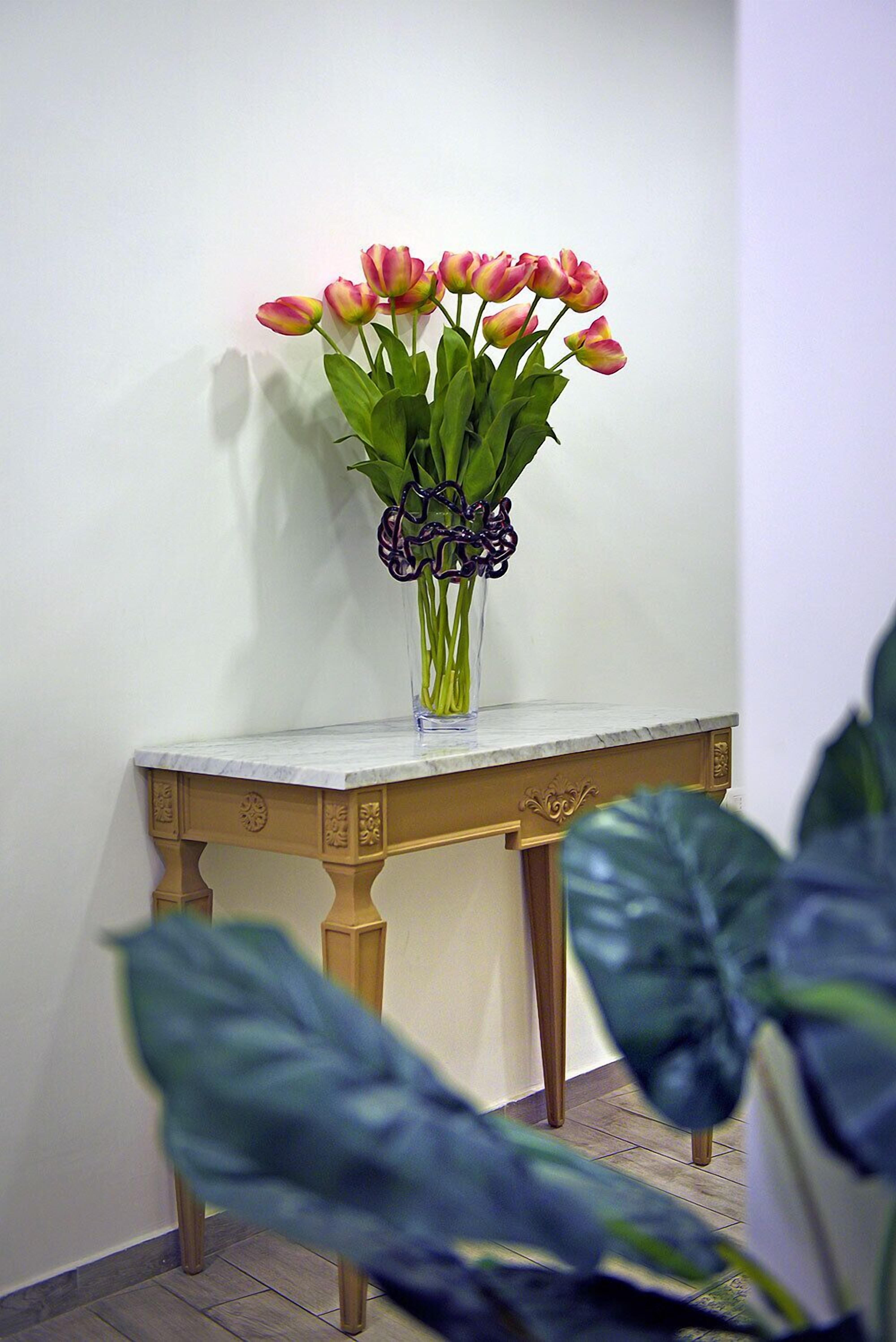 A vase with flowers on a table against a wall.