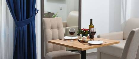 A dining area with a table set for two, featuring a wine glass, a bottle of wine, and a small plant.