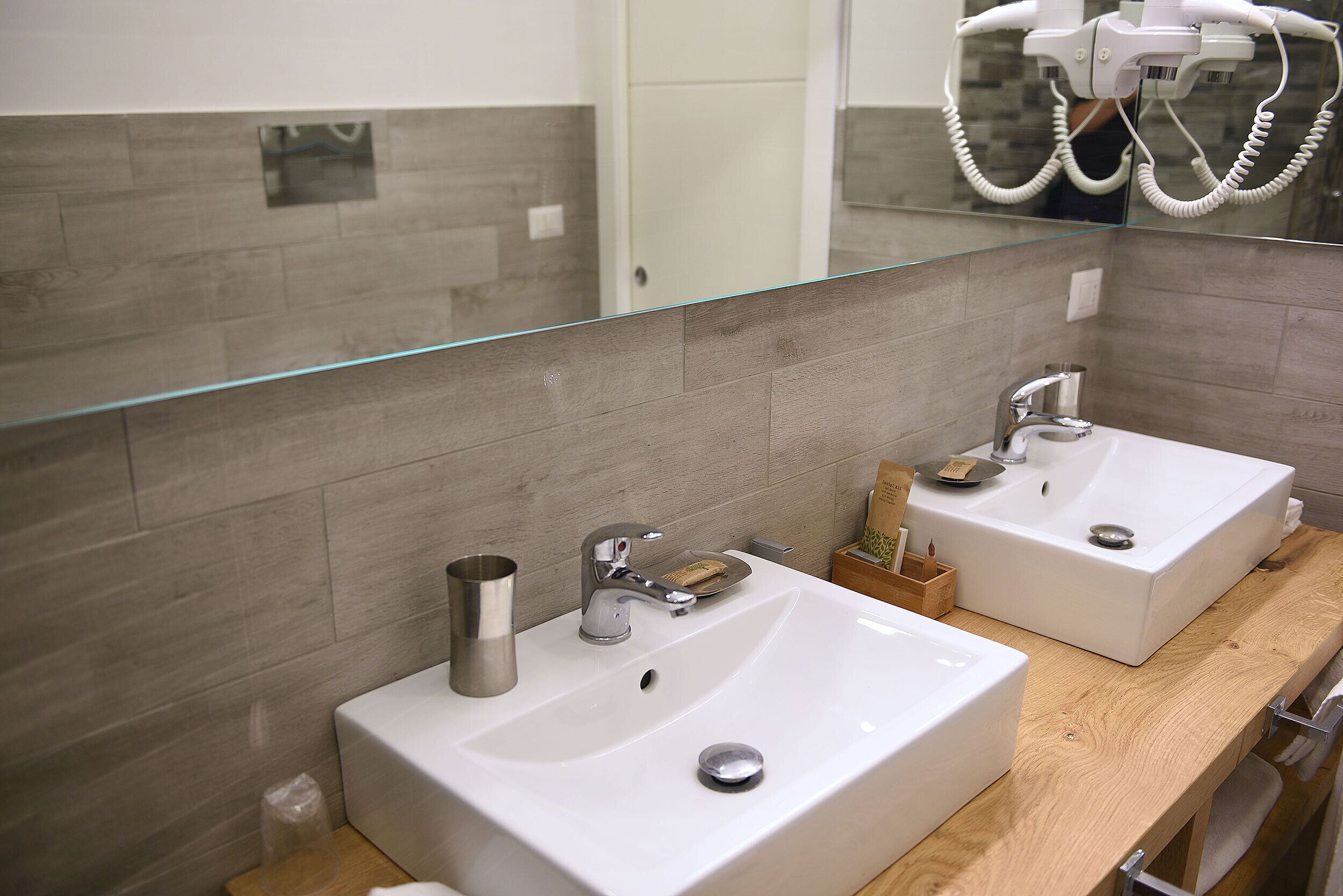 A bathroom with two sinks, a mirror, and a hairdryer.