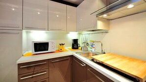 Una cocina moderna con armarios blancos, encimera de madera, microondas, cafetera y fregadero.