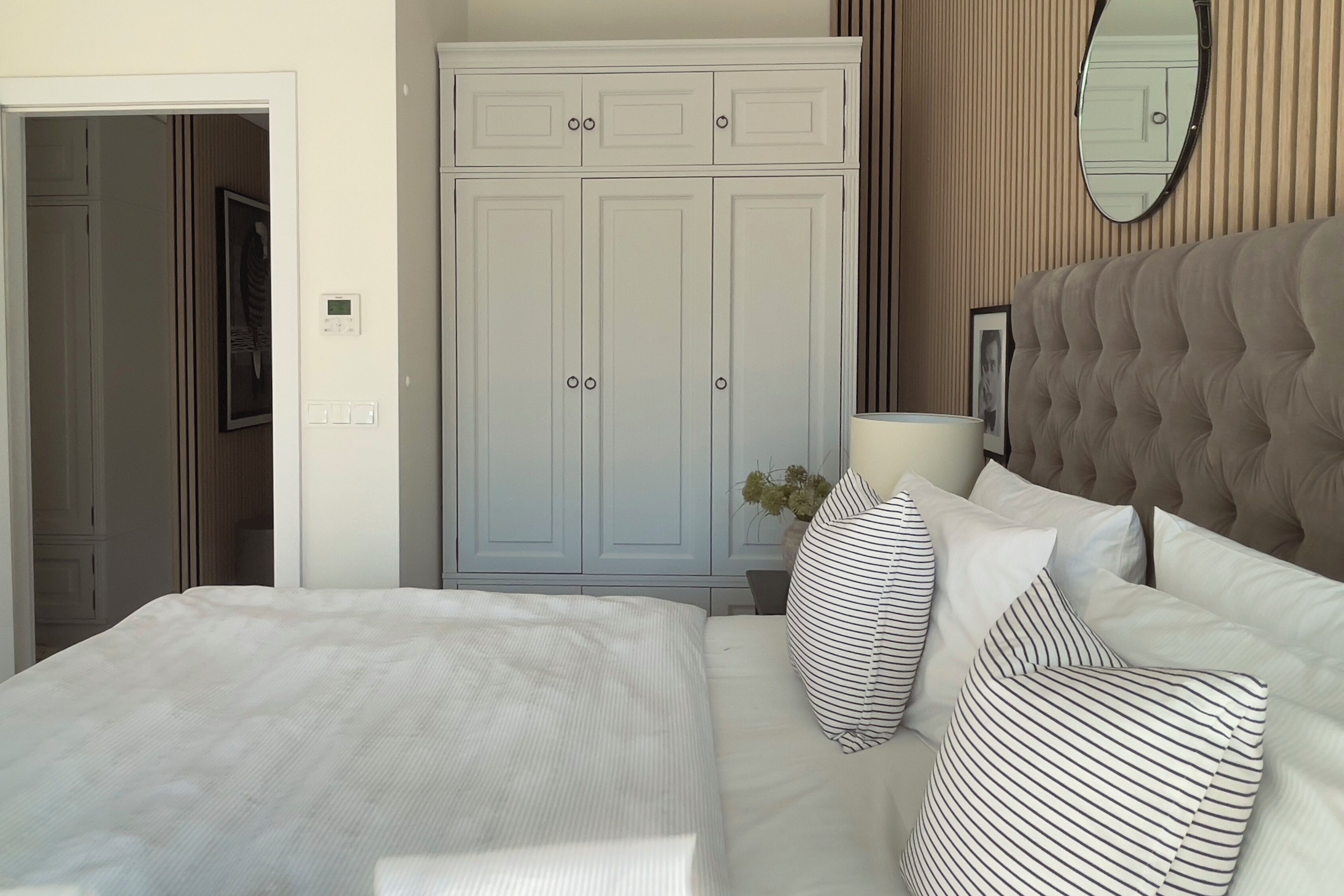 Una camera da letto con un letto, un armadio, uno specchio e un comodino.