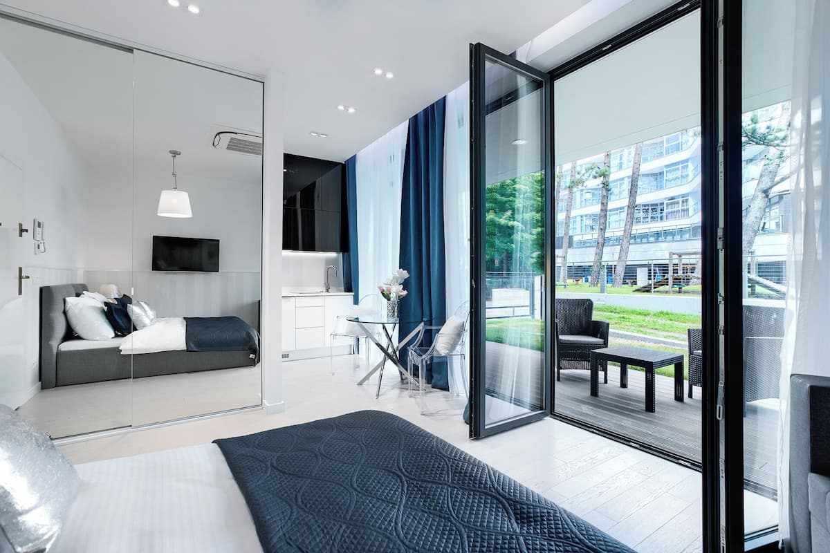 Ein modernes Hotelzimmer mit einer Couch, einem Bett, einer Glastür, die zu einem Außenbereich führt, und einem an der Wand befestigten Fernseher.