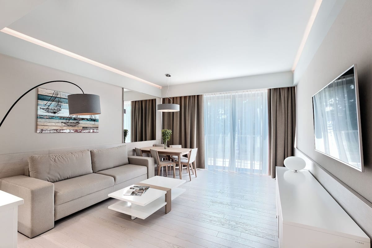 Ein modernes Wohnzimmer mit Sofa, Couchtisch, Essbereich und Fernseher.