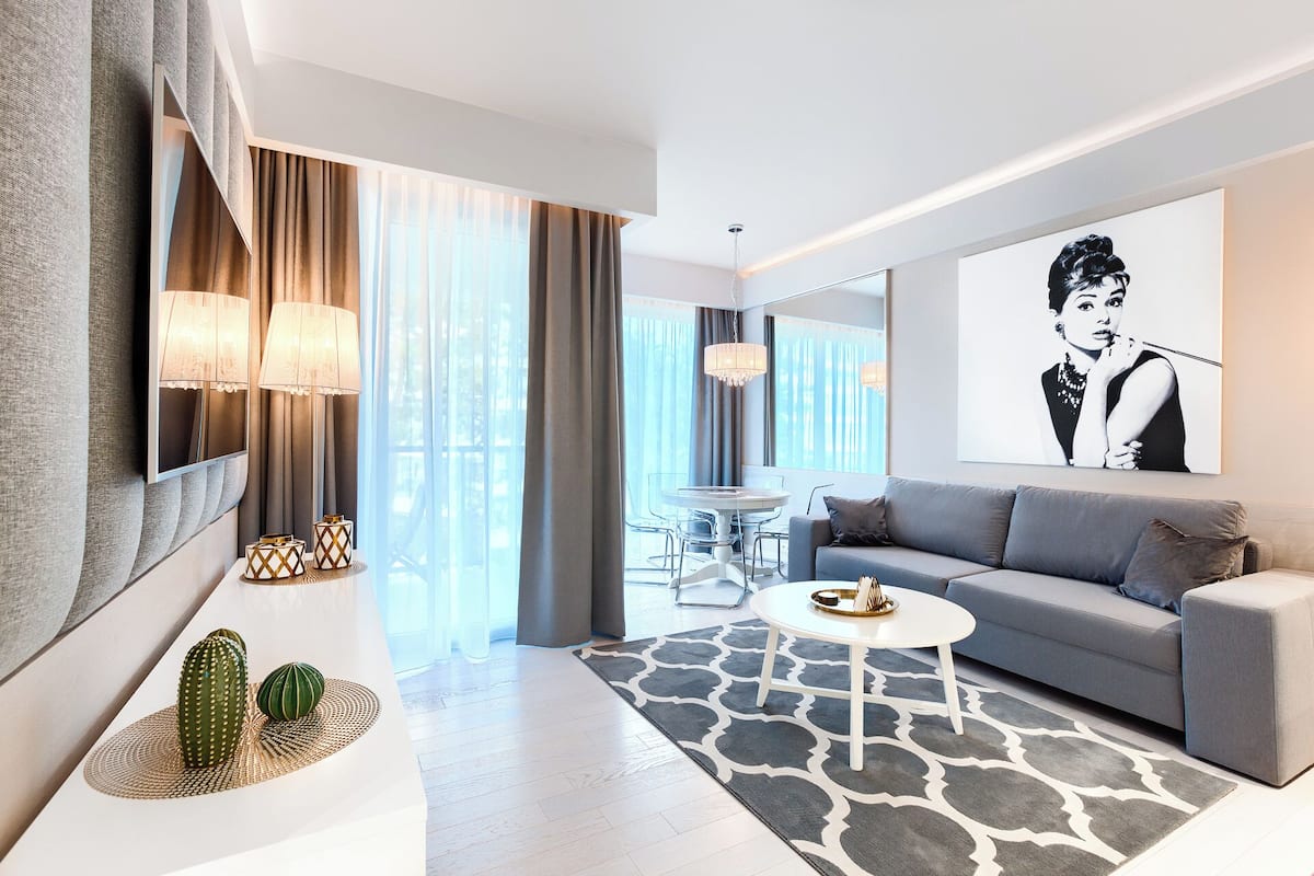 Ein modernes Wohnzimmer mit einem grauen Sofa, einem runden Couchtisch und einem großen Gemälde an der Wand.