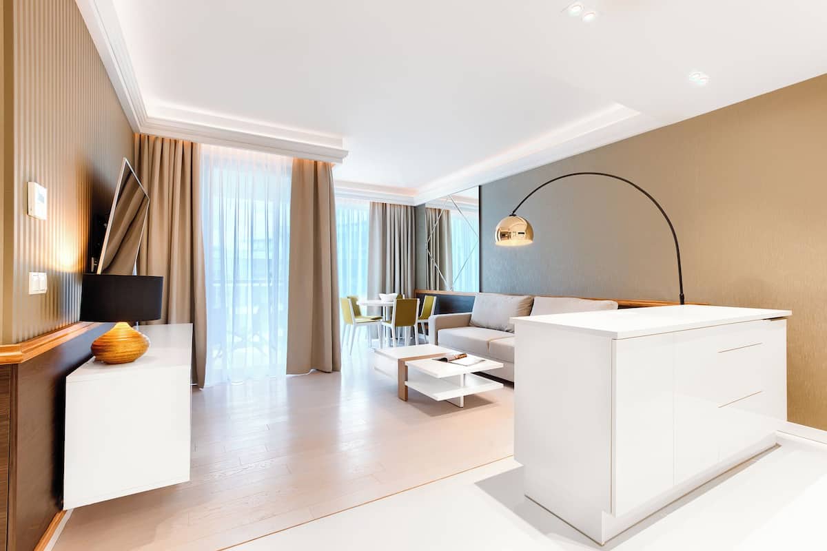 Ein modernes Hotelzimmer mit einer Couch, einem Couchtisch, einer TV-Konsole und einem Schreibtisch.