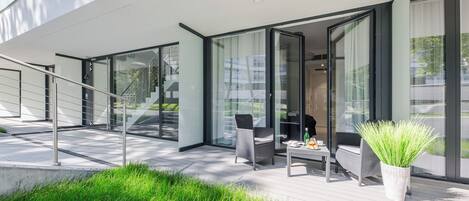 A modern outdoor seating area with glass doors, a staircase, and a small table with a plant.