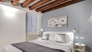 A bedroom with a bed, a window, a wall-mounted artwork, and a bedside table. - San Marco - Campo Manin by Wonderful Italy (Venice)