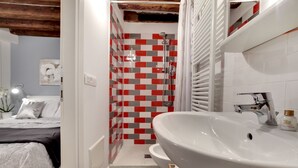 A bathroom with a white sink, shower, and tiled walls. - San Marco - Campo Manin by Wonderful Italy (Venice)