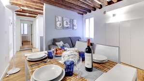 A dining area with a table set for four, a bottle of wine, and a bowl of fruit. - San Marco - Campo Manin by Wonderful Italy (Venice)