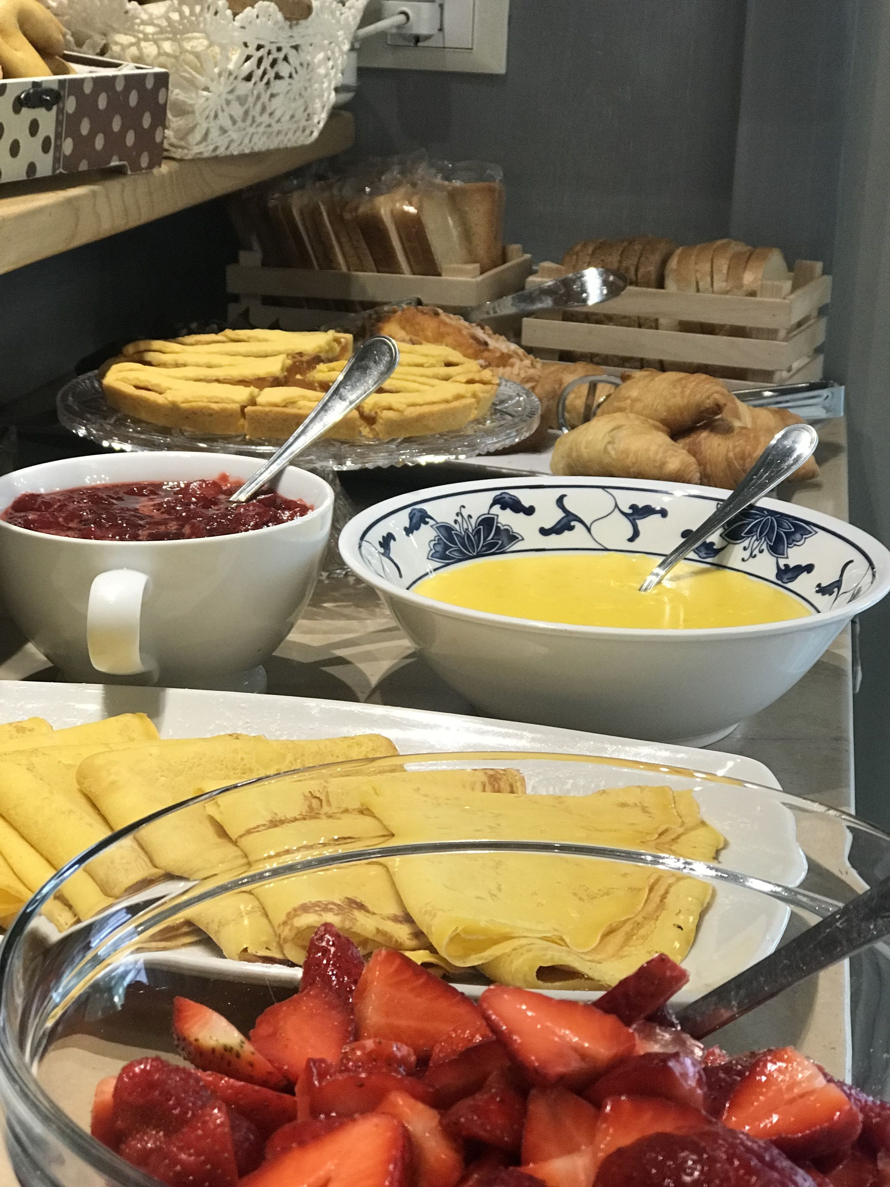 A buffet with various breakfast items including pastries, fruit, and bowls of soup.