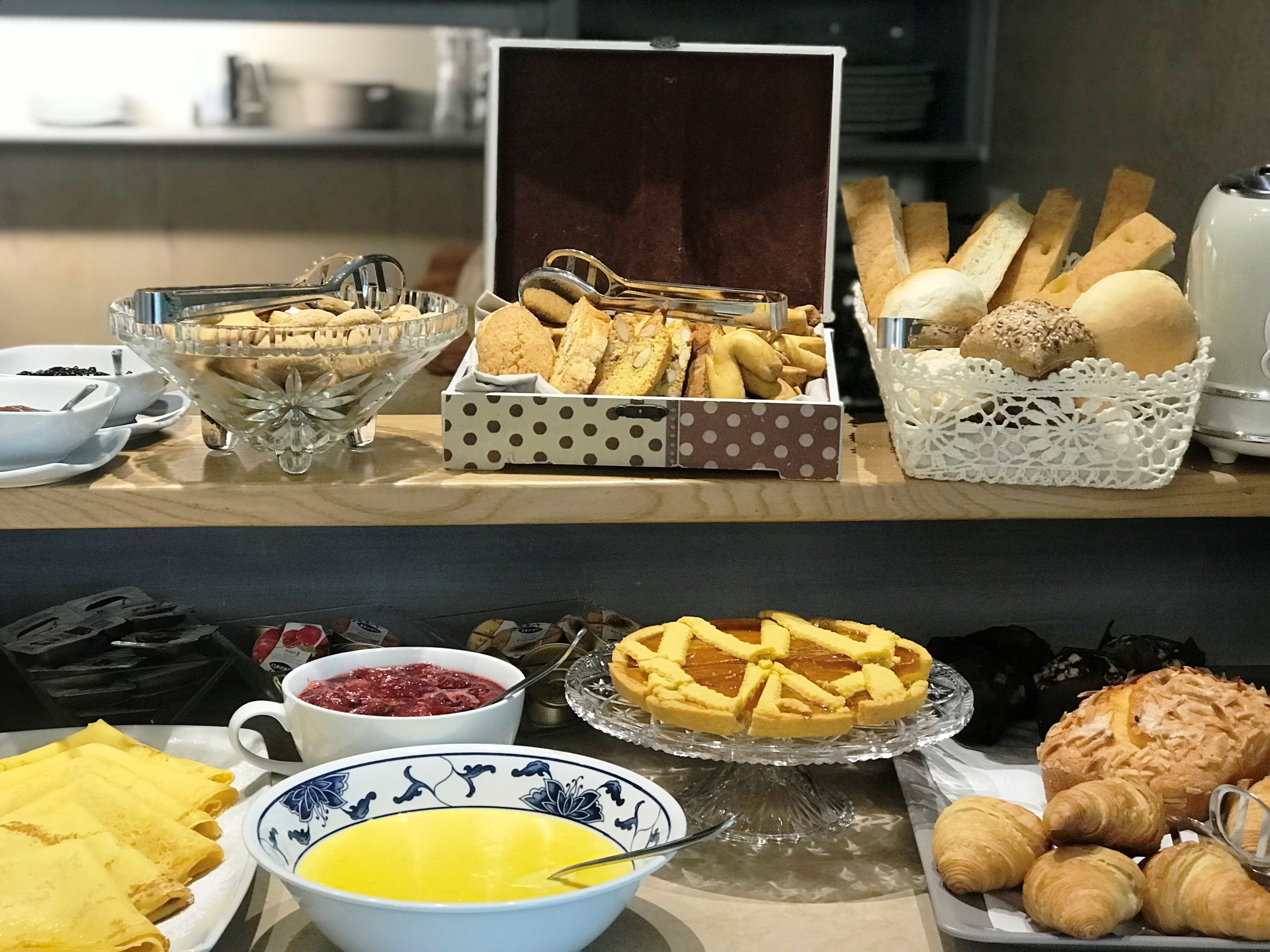 A buffet with various food items including pastries, bread, and desserts.
