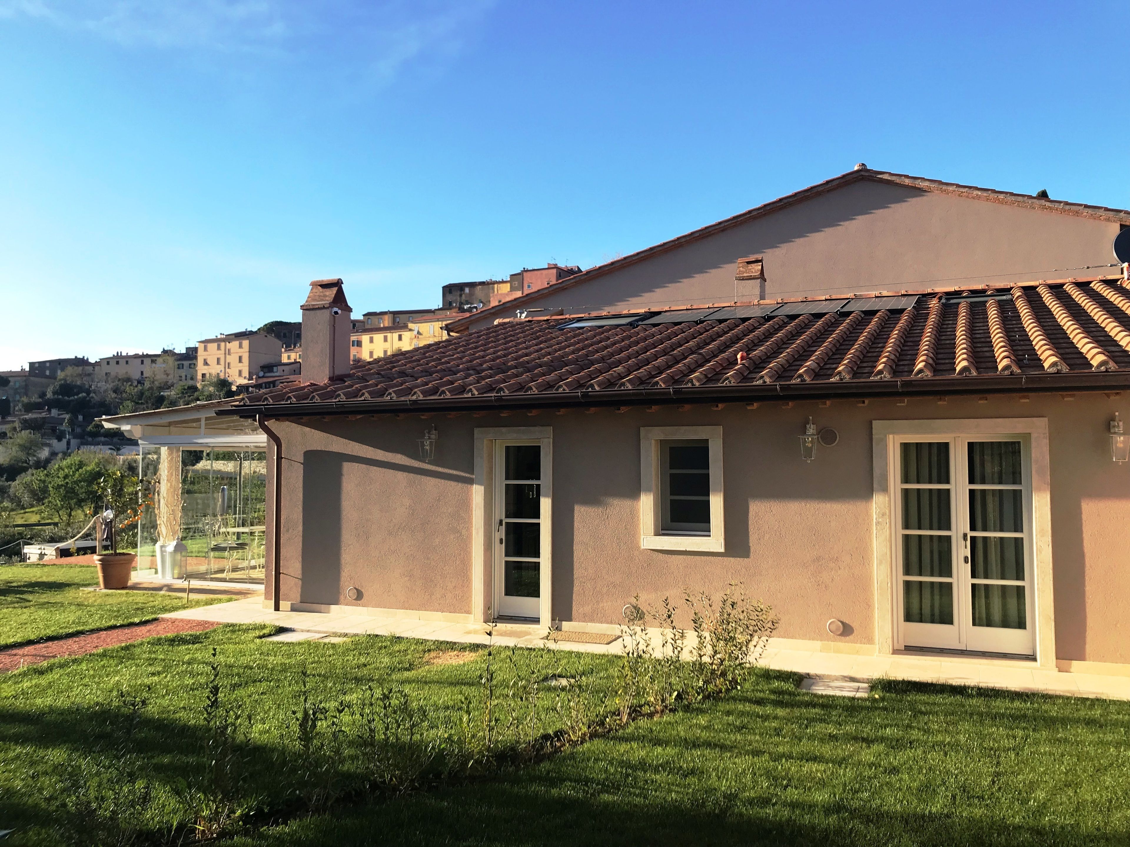 Une maison à deux étages, avec un toit en tuiles, un petit jardin et un ciel dégagé.