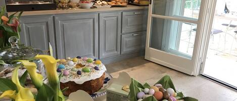 A kitchen with a variety of food items on the counter, including a cake with colorful decorations, a bowl of Easter eggs, and a glass container with a lid.