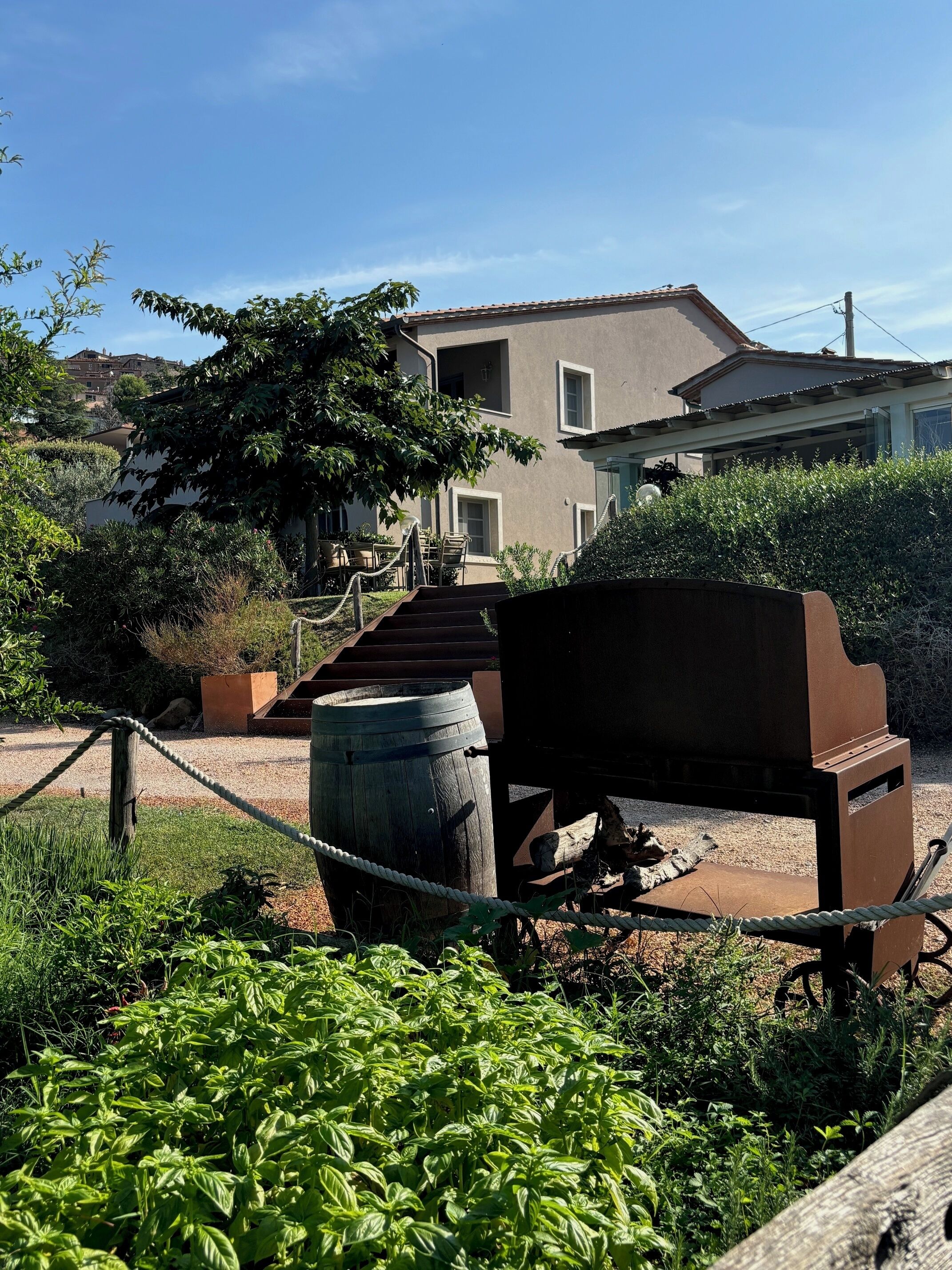 Un'area esterna rustica con una panchina in legno, un barbecue e un recinto in corda.