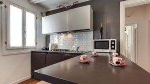 A modern kitchen with a dark countertop, white cabinets, and a microwave. - Ca' d'Oro Design by Wonderful Italy (Venice)