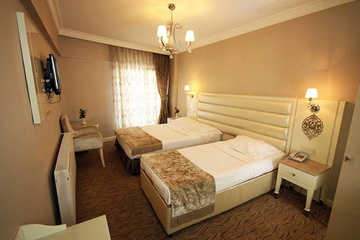 Une chambre d’hôtel avec deux lits, un bureau, une chaise, une télévision et un lustre.
