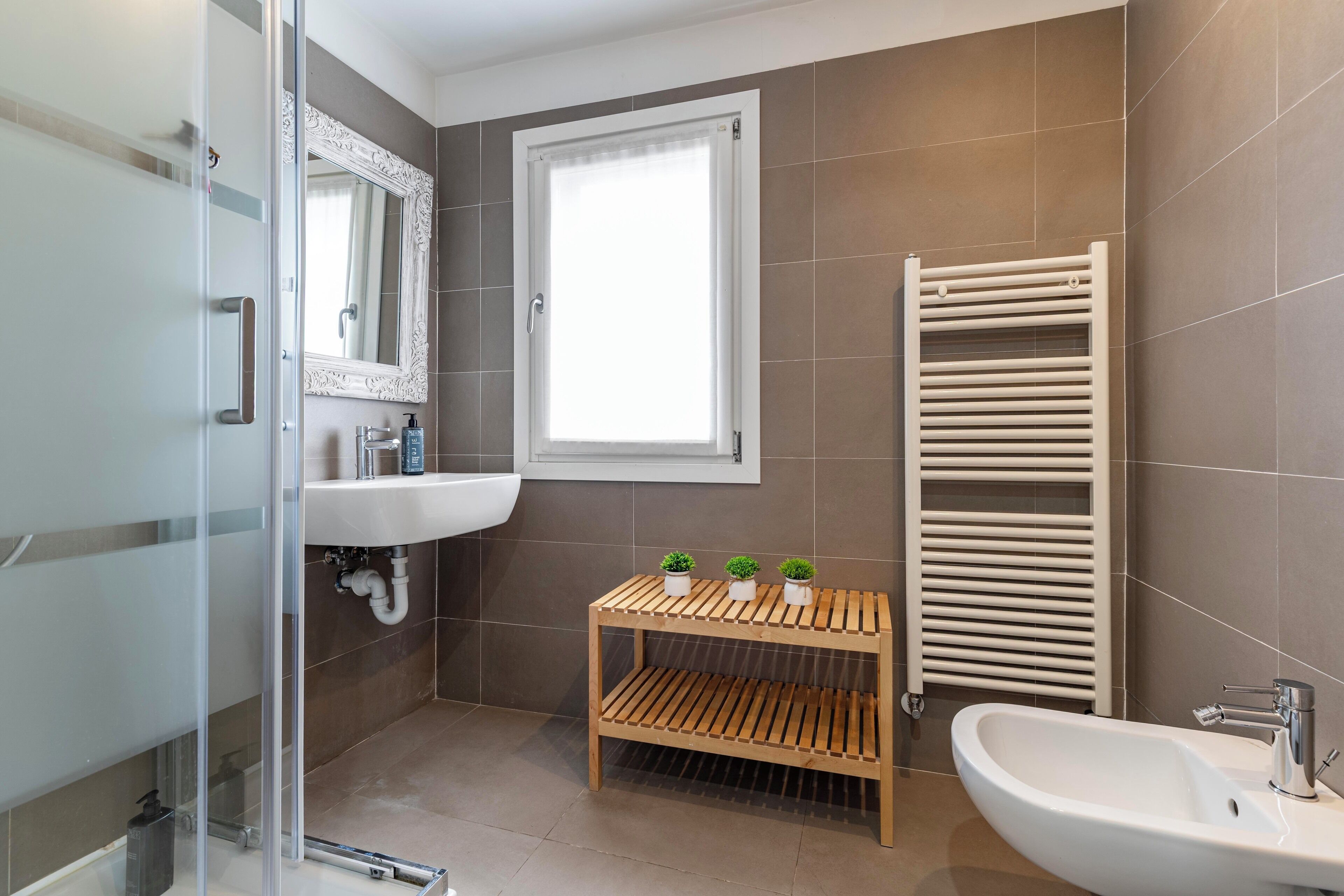 Ein modernes Badezimmer mit einer Glasdusche, einem weißen Waschbecken, einer Holzausstattung und einem Handtuchhalter.