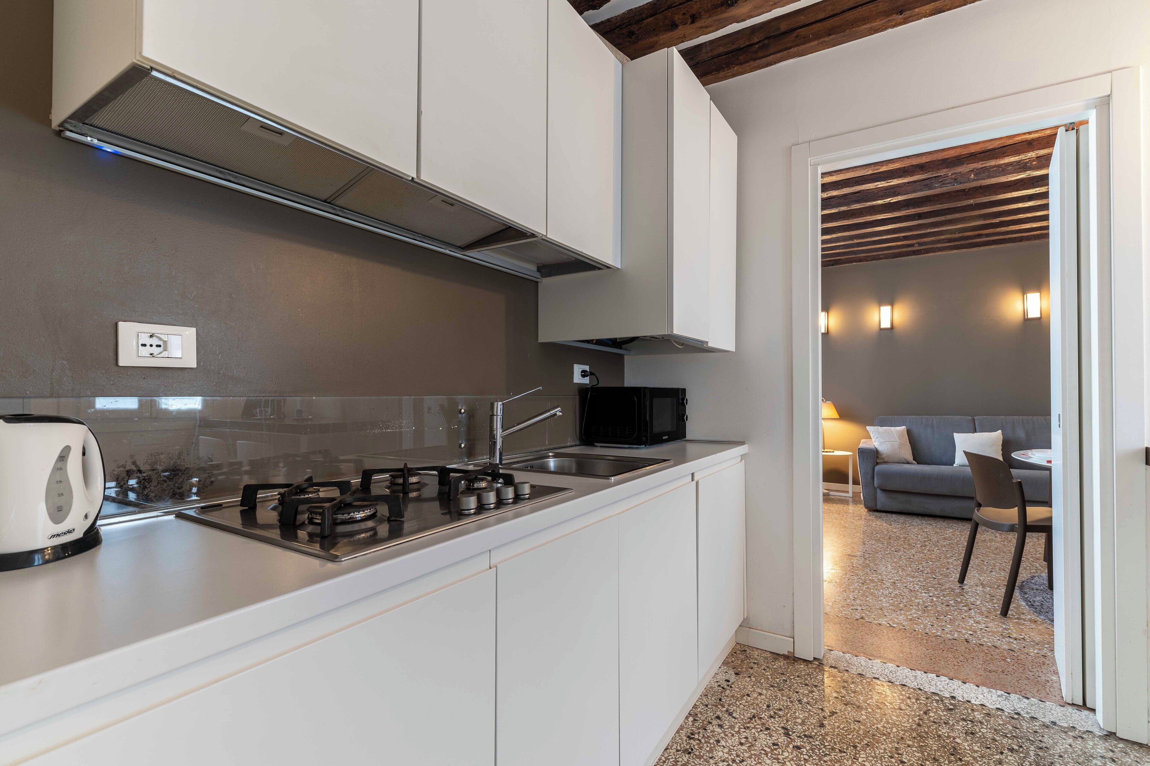 Une cuisine moderne avec des armoires blanches, une cuisinière en acier inoxydable et un four à micro-ondes.