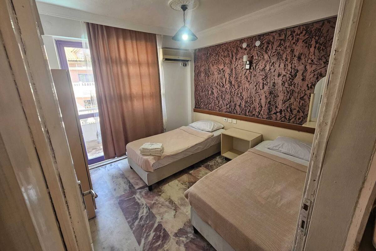 Une chambre d’hôtel avec deux lits, un grand miroir, un ventilateur de plafond et une vue sur l’extérieur.