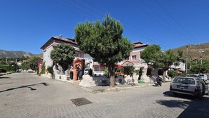 Una calle empedrada bordeada de edificios, un coche aparcado y un árbol.