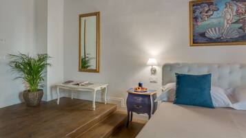 A bedroom with a bed, a nightstand, a lamp, a mirror, and a painting.
