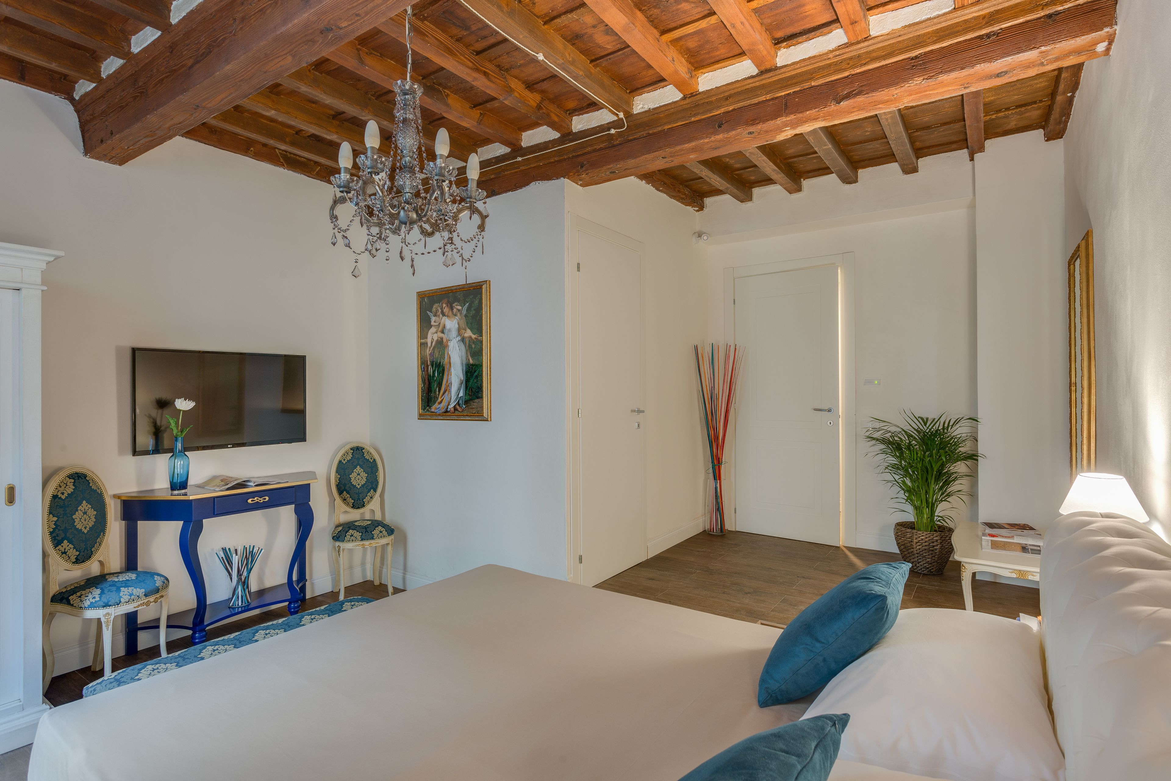 Ein Schlafzimmer mit einem großen Bett, einem Fernseher, einer Chandelier und einem Schreibtisch mit Stühlen.