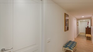 A hallway with a white door, a bench, and a small table with a potted plant. - Residenza D'Epoca Sant Anna (Florence)
