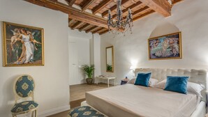 A bedroom with a large bed, a chair, and two paintings on the walls. - Residenza D'Epoca Sant Anna (Florence)