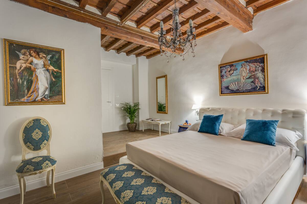 Une chambre avec un grand lit, une chaise et deux tableaux accrochés aux murs.
