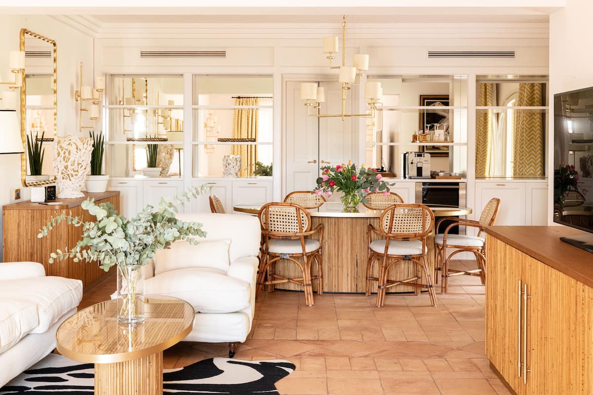 A modern kitchen with white cabinetry, a wooden island, and a dining area with wicker chairs.