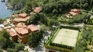 Zona residencial con varias casas, una cancha de tenis y el mar de fondo.