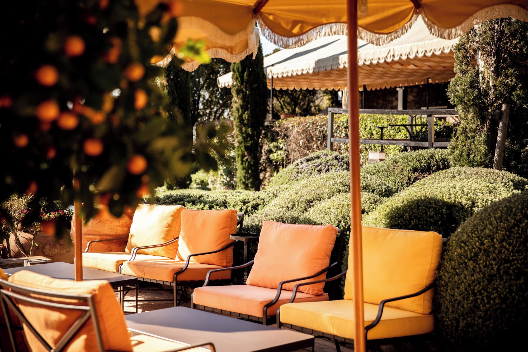 Outdoor seating with orange cushions, a table, and a canopy.