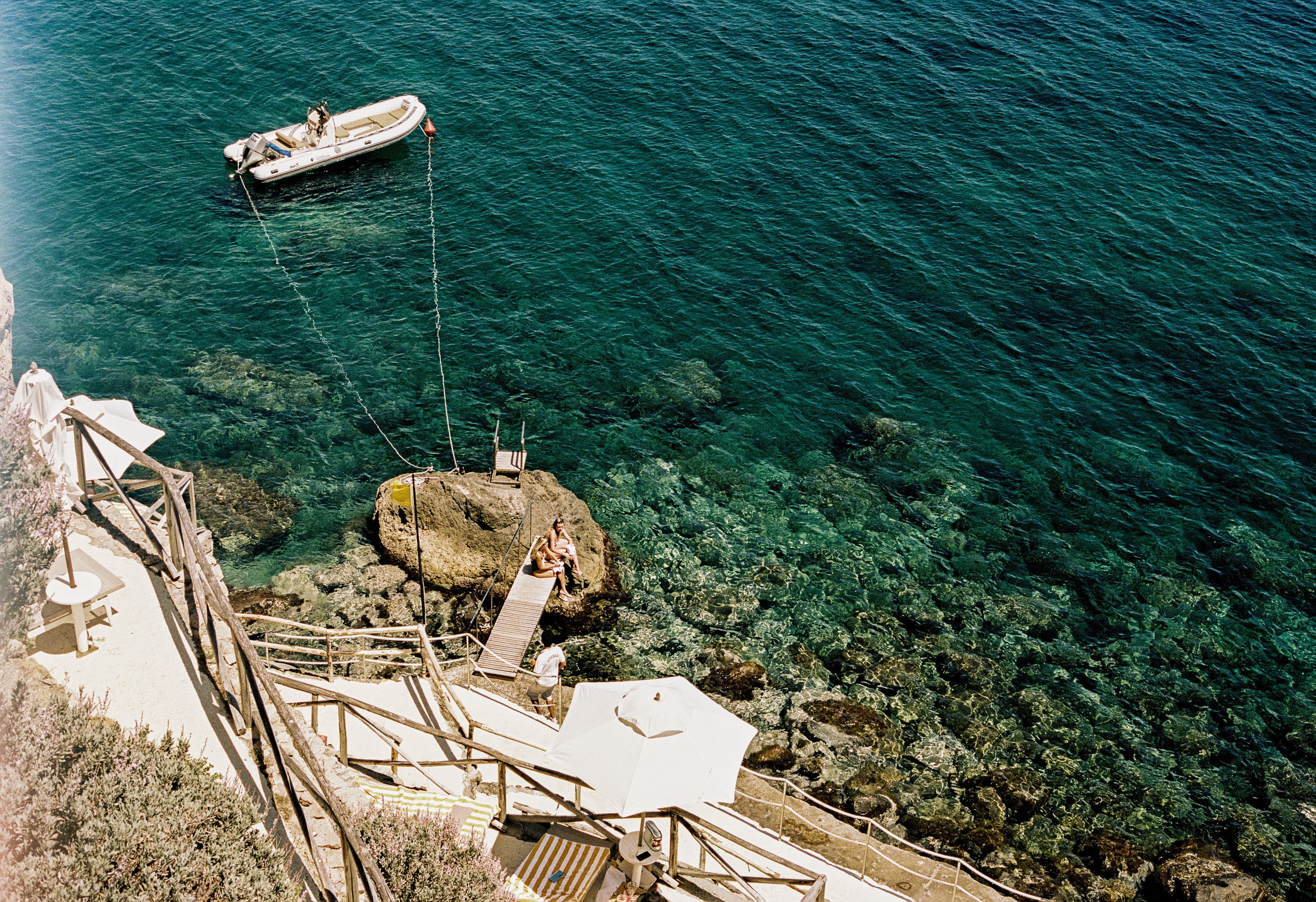 A boat tied to a dock with clear water and rocky terrain.