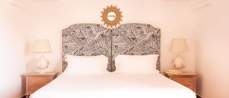 A bed with a patterned headboard, two bedside tables with lamps, and a sun-shaped decoration above the headboard.