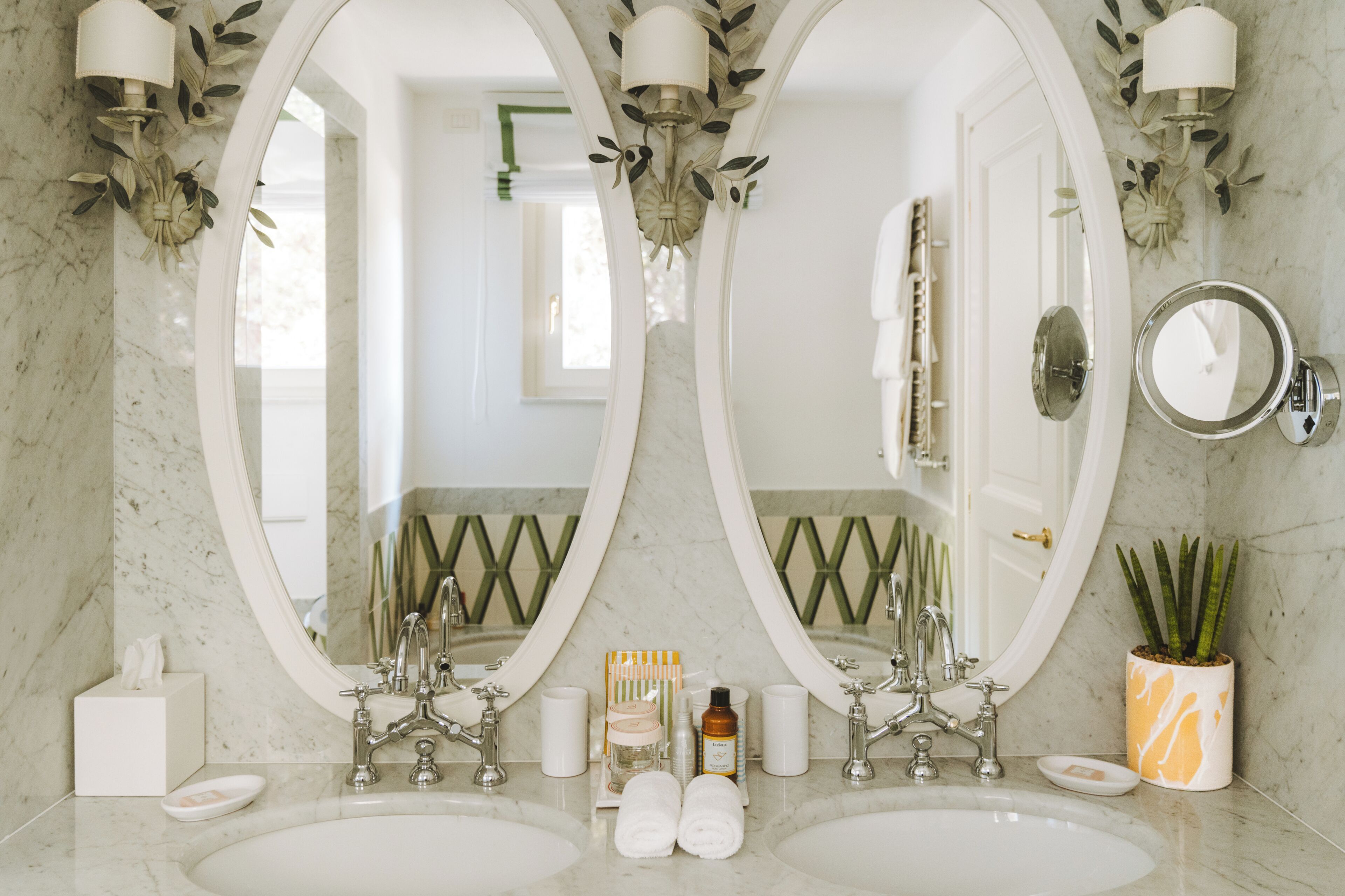 Une salle de bain avec deux lavabos, un grand miroir et une plante en pot.