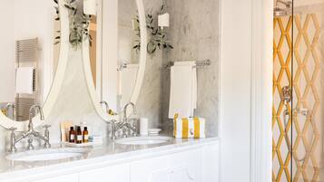 A bathroom with two sinks, a large mirror, and a shower area.