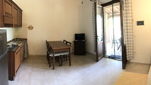 Cocina compacta con una mesa de comedor, sillas, refrigerador y televisor.