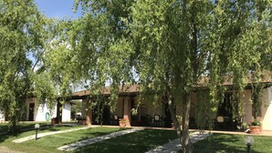 Un patio con un sendero empedrado, zona de estar al aire libre y un edificio con tejado de baldosas.