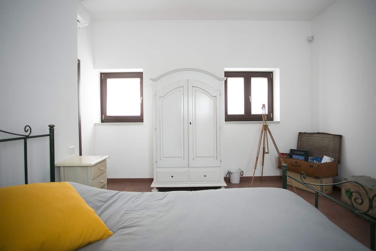 A bedroom with a bed, a wardrobe, a desk, and a window.