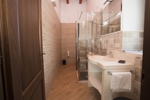 Bathroom features a glass-enclosed shower, white sink, and towel rack.