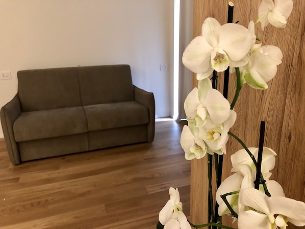 A room with a grey sofa and a wooden floor.