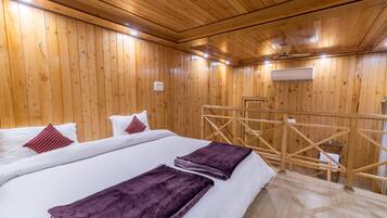 A wooden-paneled room with a bed, pillows, a blanket, and a wooden ladder.