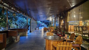Un vaste espace intérieur avec un long couloir, des meubles en bois et de grandes fenêtres donnant sur un jardin.