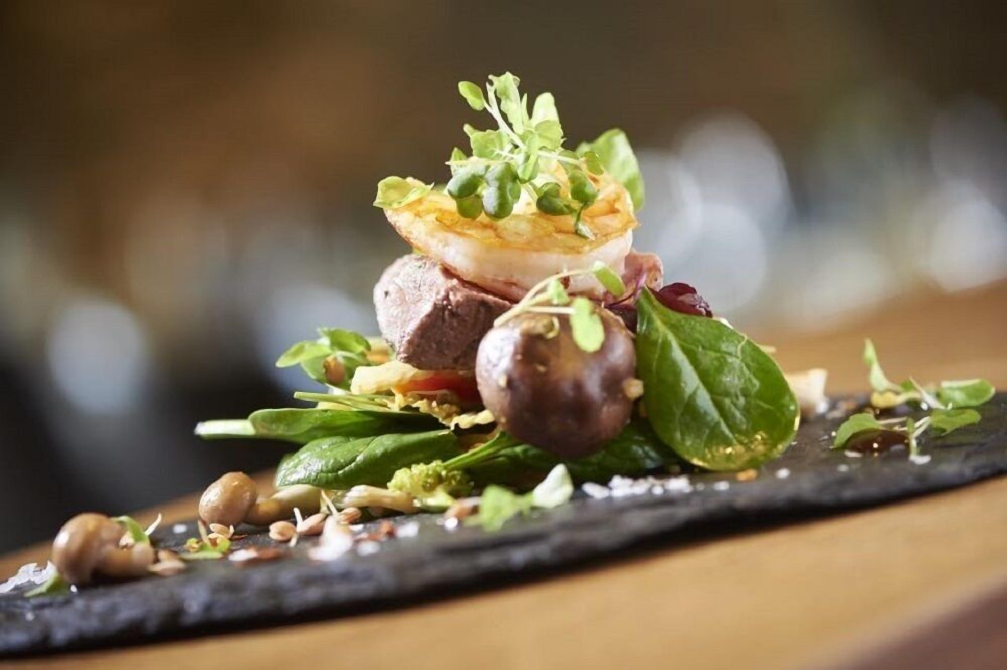 A gourmet dish with various ingredients and garnishes on a slate plate.