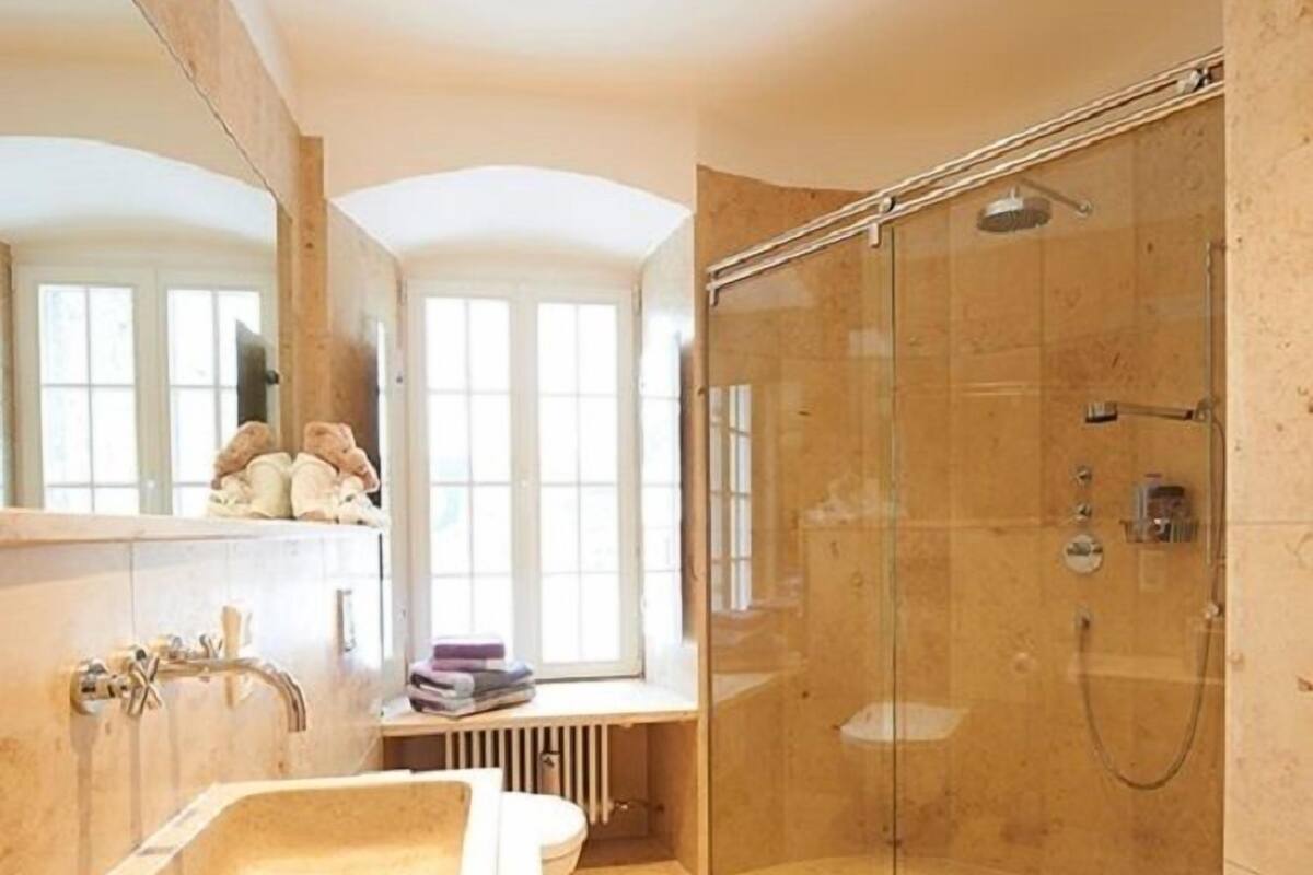 Un baño moderno con un lavamanos grande, una ducha con cerramiento de vidrio y una ventana que proporciona luz natural.